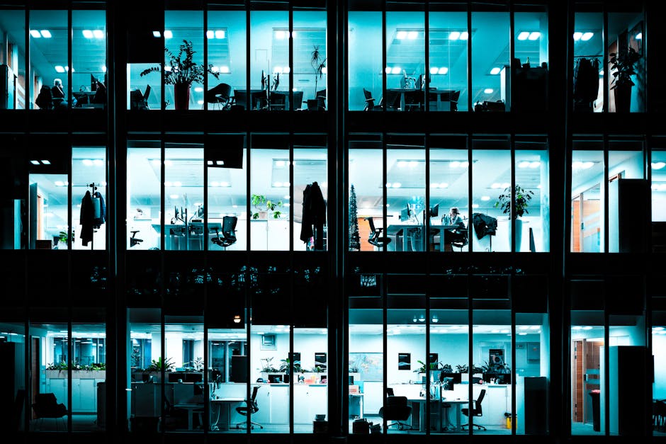 Night view of an illuminated modern office building showcasing workspaces.